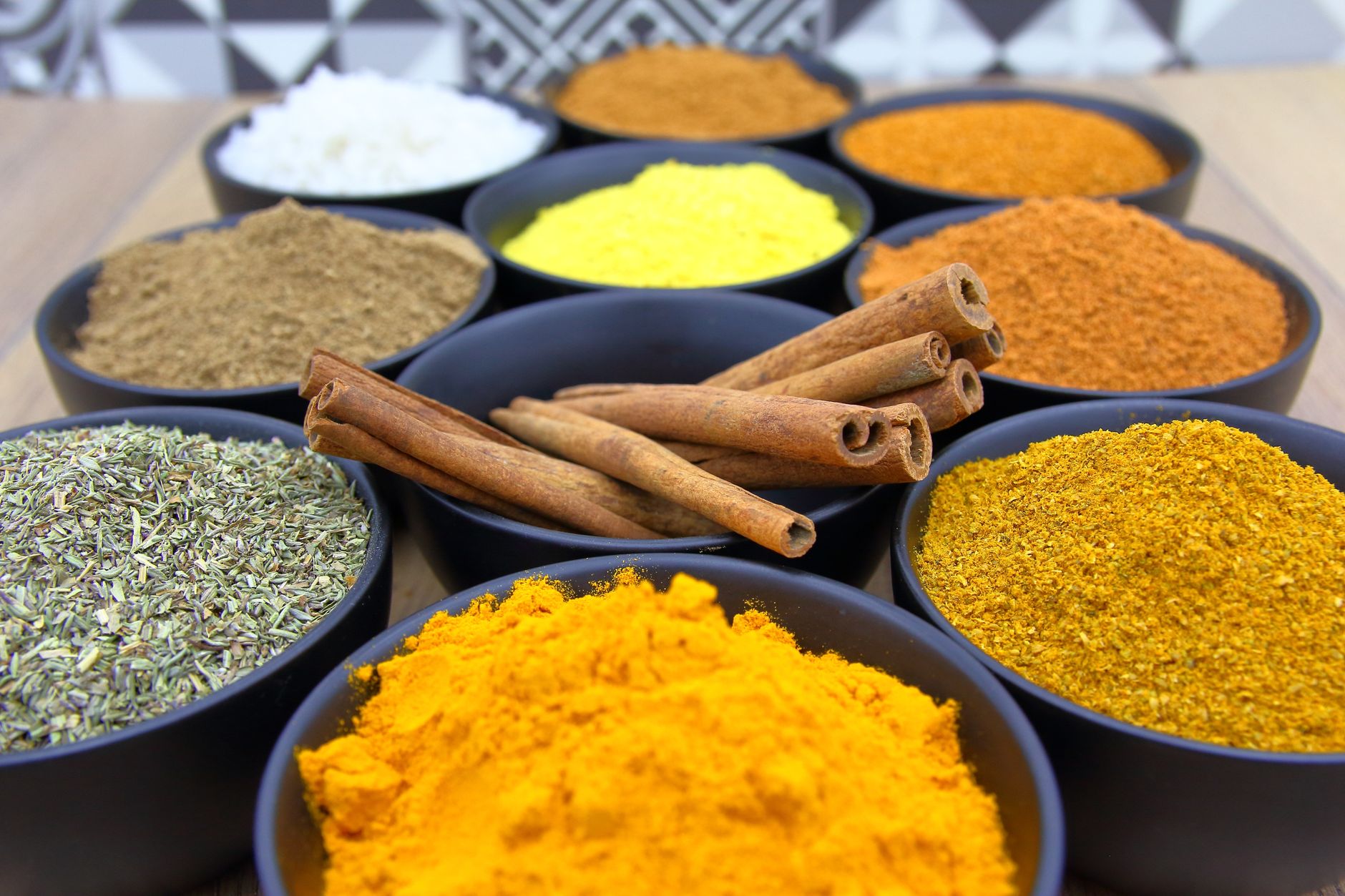 assorted spices in bowls with cinnamon sticks